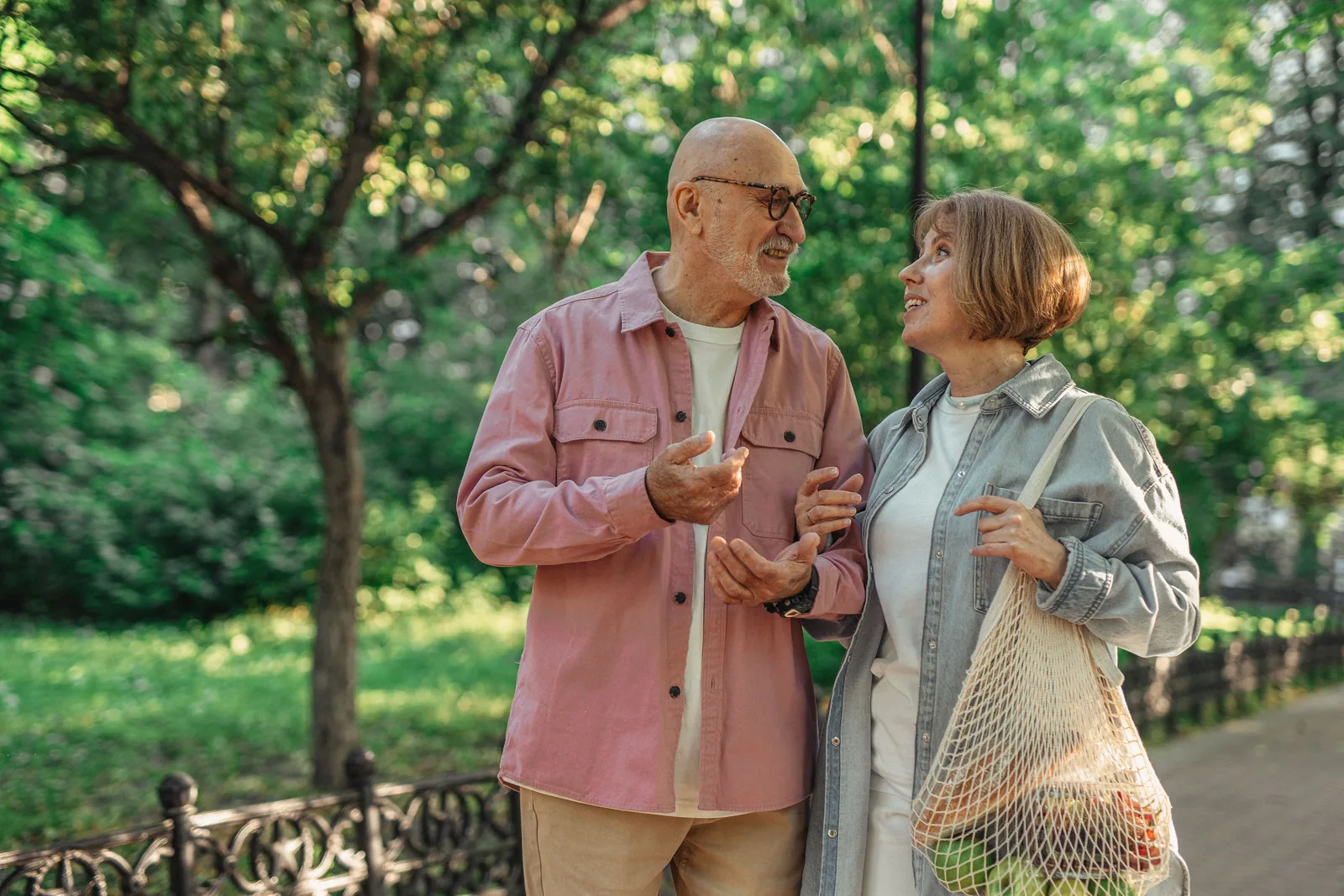 A couple walking and talking on a tree-lined park path